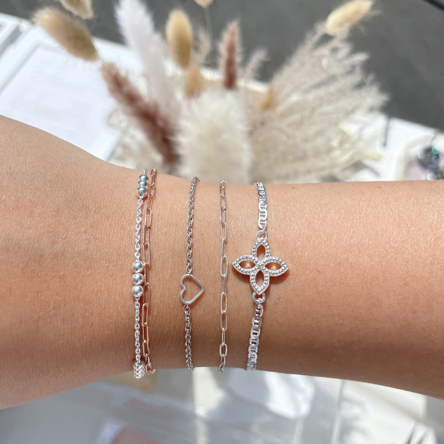 Close-up of a wrist wearing multiple silver bracelets with a blurred background