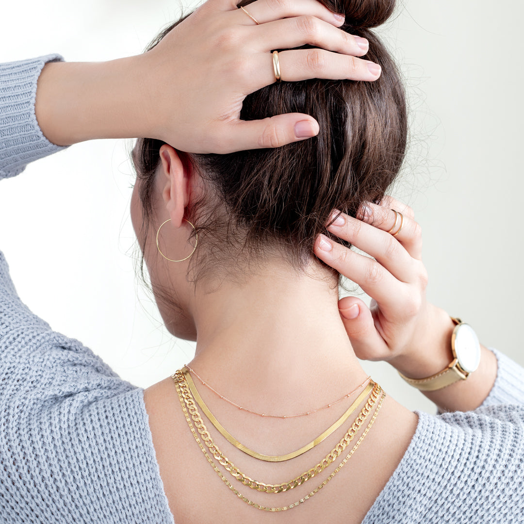 Model wearing multiple necklaces layered