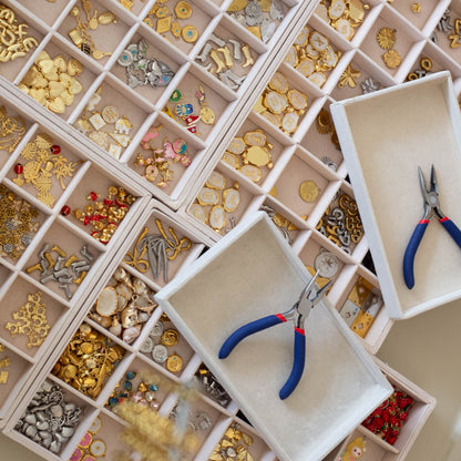 Jewelry-making supplies including beads, clasps, and pliers in a organized display case.
