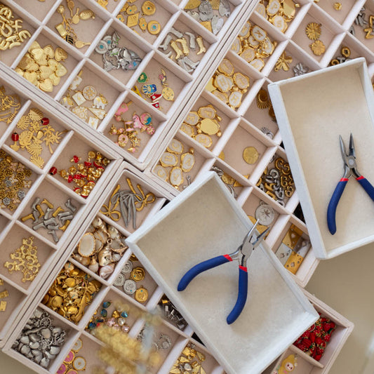 Jewelry-making supplies including beads, clasps, and pliers in a organized display case.